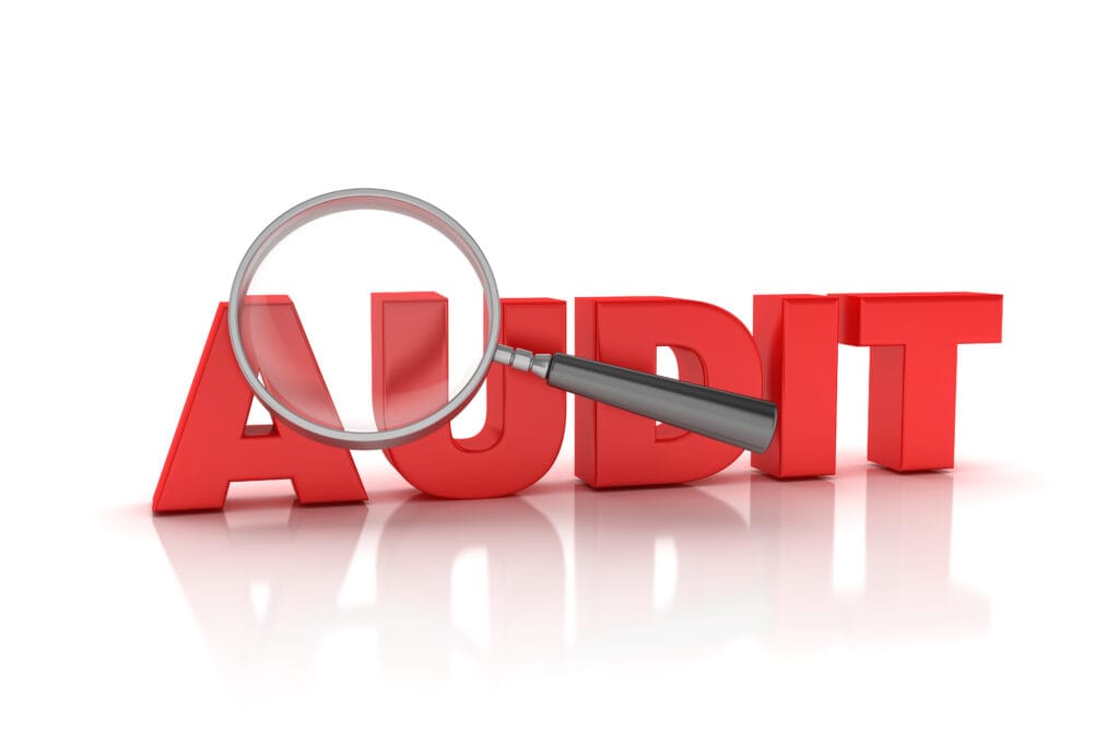 Magnifying Glass overlooking the word AUDIT colored in red as a 3D rendering